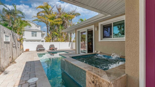 Un jardin avec une piscine, un jacuzzi et un patio couvert.