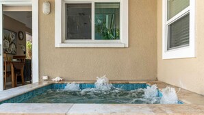 Un bain à remous avec jets d’eau, une bordure carrelée et une fenêtre au-dessus.