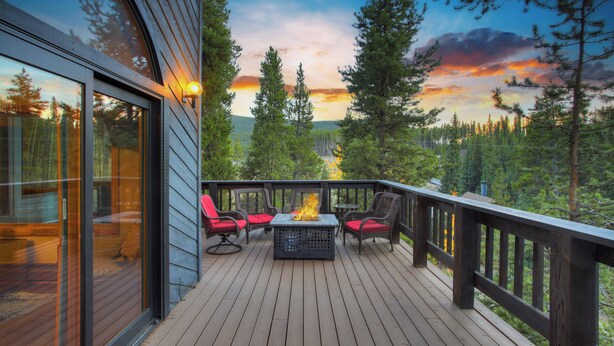 A wooden deck with outdoor seating and a fire feature, overlooking a forested landscape. - Spacious 5BR Breckenridge Cabin, Game Room, Hot Tub, Minutes to Breck Ski Resort (Breckenridge)