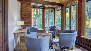 A cozy cabin interior with a 'Drink Local' sign, large windows, and rustic wooden walls. - Spacious 5BR Breckenridge Cabin, Game Room, Hot Tub, Minutes to Breck Ski Resort (Breckenridge)