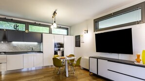 A modern kitchen with a dining area, built-in appliances, and a large TV. - GuestHost - Modern Apartament with large terrace (Florence)