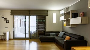A modern living room with a black sectional sofa, a wooden coffee table, and a sliding glass door leading to a balcony. - GuestHost - Modern Apartament with large terrace (Florence)