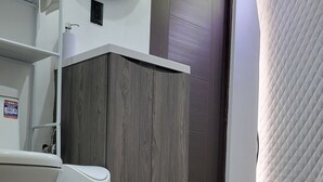 Ein Badezimmer mit Toilette, Waschbecken, Spiegel und einem Holzschrank.