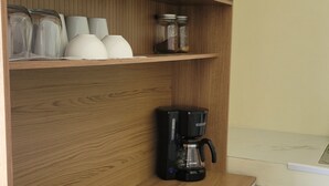 Eine Küche mit Holzausstattung, einer Kaffeemaschine und Gläsern auf den Regalen.