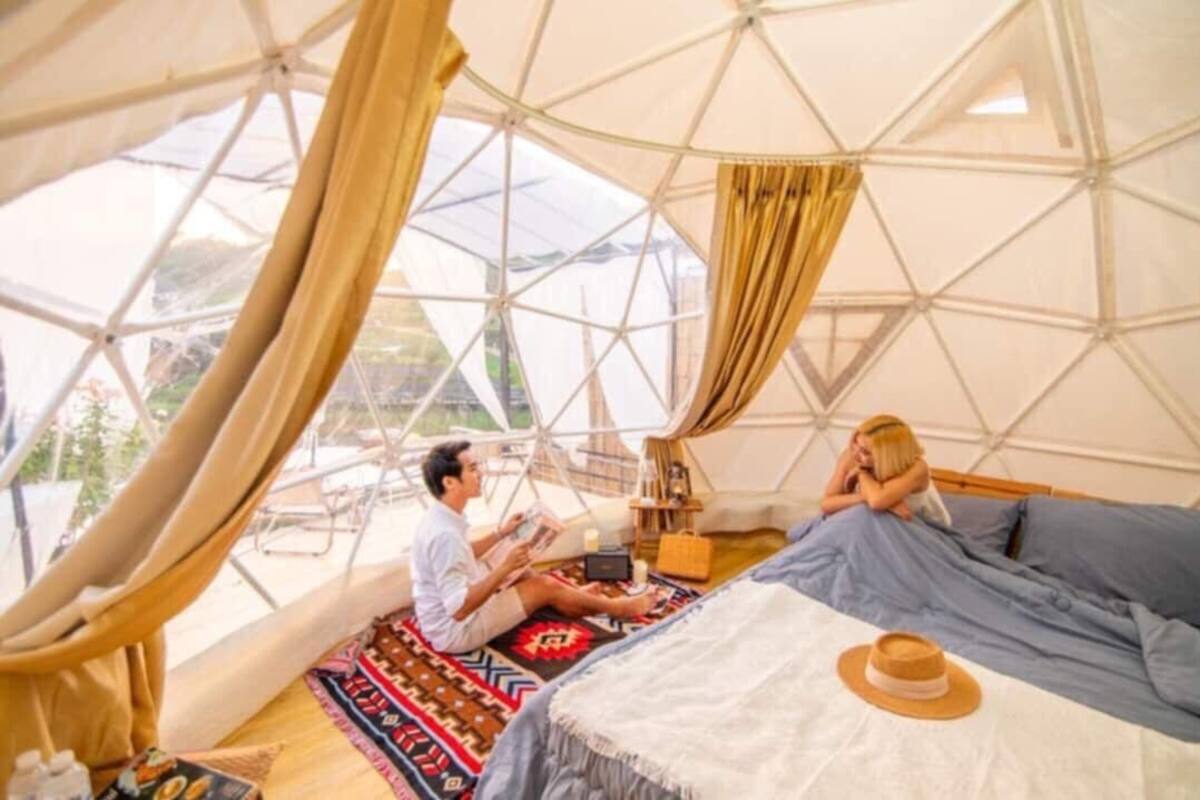 A spacious tent with a large bed, a small table, and a chair.