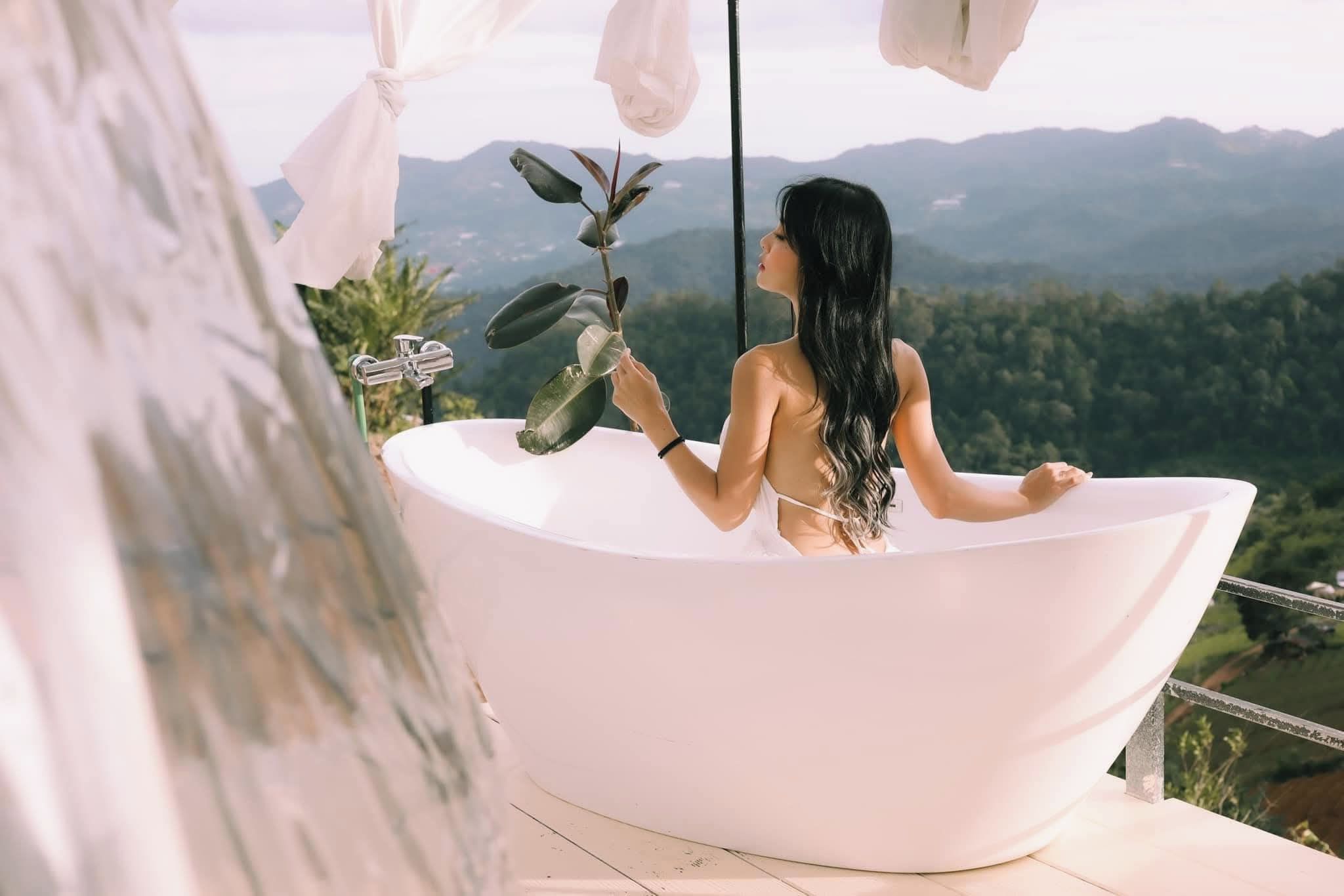 Eine Frau in einer Badewanne mit Blick auf Berge.