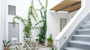 A courtyard with a staircase, white walls, and potted plants.