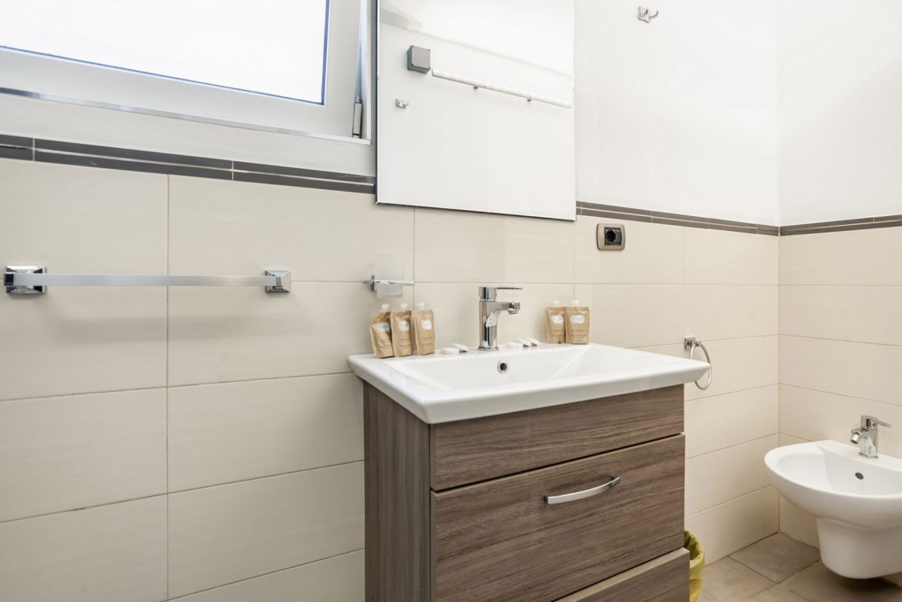 Un baño con lavamanos blanco, mueble de madera y un bidé.