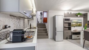A modern kitchen with a built-in microwave, a refrigerator, and a coffee machine.