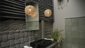 A bathroom with a black sink, a mirror, and a decorative wall. - THE BALI HOUSE (Bhopal)