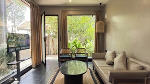 A modern living room with a sofa, two armchairs, a coffee table, and a television. - THE BALI HOUSE (Bhopal)