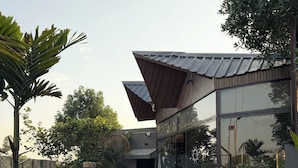 A modern building with a brick pathway, surrounded by potted plants and a stone wall. - THE BALI HOUSE (Bhopal)
