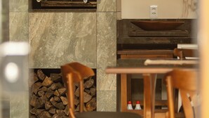 Eine moderne Küche mit Einbauofen, einem Holzespeisetisch mit Stühlen und einer Steinwand mit Holzscheinspeicher.