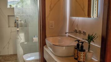 Un baño moderno con ducha envuelta en vidrio, inodoro blanco y bañera independiente.
