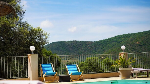 A poolside area with lounge chairs and a view of a mountainous landscape.