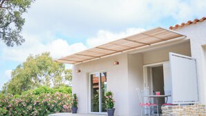 A modern house with a covered patio, a glass door, and a small outdoor seating area.