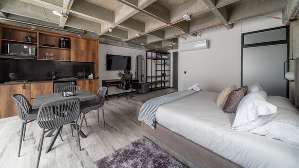 Un espacio habitable moderno y abierto con cocina, comedor y dormitorio.