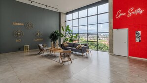 A spacious living area with a large window, a grey wall with city names, a red accent wall, and a modern furniture arrangement.