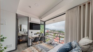 A modern bedroom with a large bed, a desk, and a view of the city.