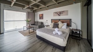 Un dormitorio moderno con una cama grande, un escritorio, una silla y vistas al exterior.