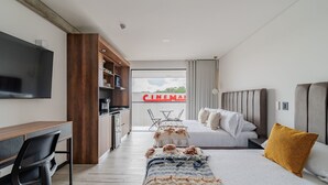 Una habitación de hotel moderna con cama, escritorio, televisor y vistas al exterior.