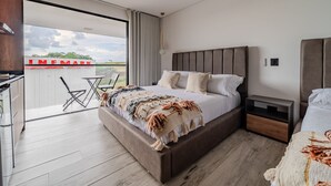 Un dormitorio moderno con una cama grande, una mesita de noche y vistas del edificio INFMARK.
