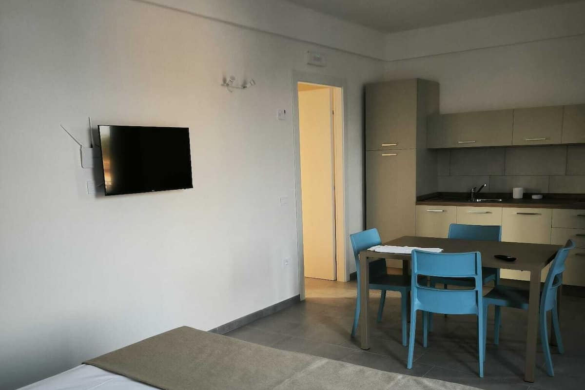 Hotellihuone, jossa on sänky, työpöytä ja pieni keittiönurkkaus.