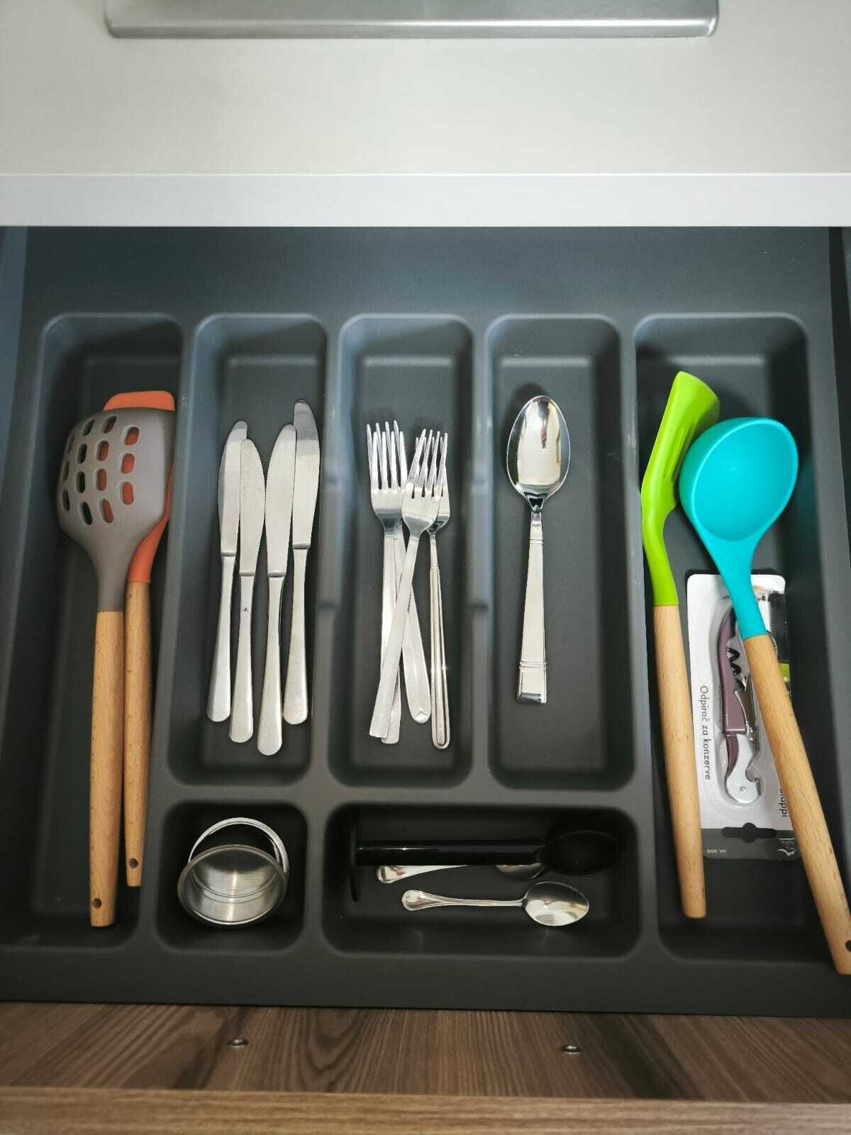 A kitchen drawer with utensils organized in compartments.
