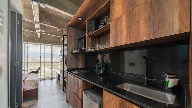 A modern kitchen with wooden cabinets, a black countertop, and a stainless steel sink.
