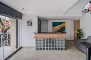 Een receptiegedeelte met een houten balie, een voetstuk van glasblokken en een kleurrijk abstract schilderij aan de muur.
