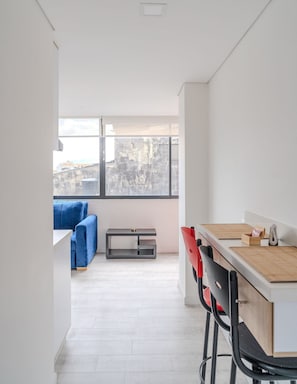 Een moderne keuken met een houten aanrecht, een rode stoel en een blauwe bank op de achtergrond.