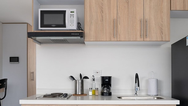 Une cuisine moderne dotée de meubles en bois, d’un four à micro-ondes, d’une machine à café et d’un évier.