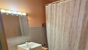 A compact bathroom with a sink, mirror, and a shower curtain.
