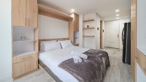 Une chambre moderne avec un lit, une armoire en bois et des étagères intégrées.