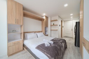 Een moderne slaapkamer met een bed, een houten garderobe en ingebouwde planken.