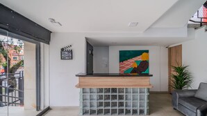 Un espace d’accueil doté d’un comptoir en bois, d’un socle en blocs de verre et d’une peinture abstraite aux couleurs vives accrochée au mur.