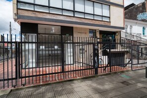 Un edificio con una cerca de metal negro, un camino de ladrillo y una escalera que conduce a una puerta con la inscripción 