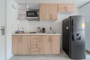 Una cucina moderna con mobili in legno, un forno a microonde integrato, un frigorifero nero e una macchina per il caffè.