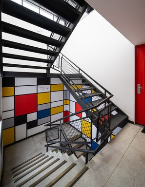 A staircase with a black metal railing and a colorful wall with geometric patterns.