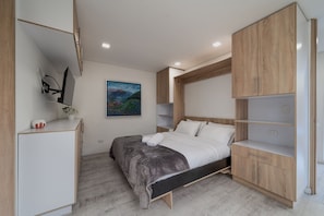 Een moderne slaapkamer met een bed, een inbouwkast en een schilderij aan de muur.