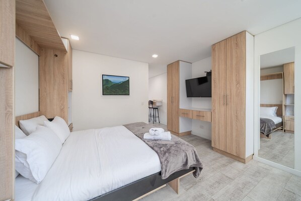 A modern bedroom with a large bed, wooden wardrobe, a TV, and a desk area. - Urban Loft @Chapinero near Campin Stadium (Bogotá)