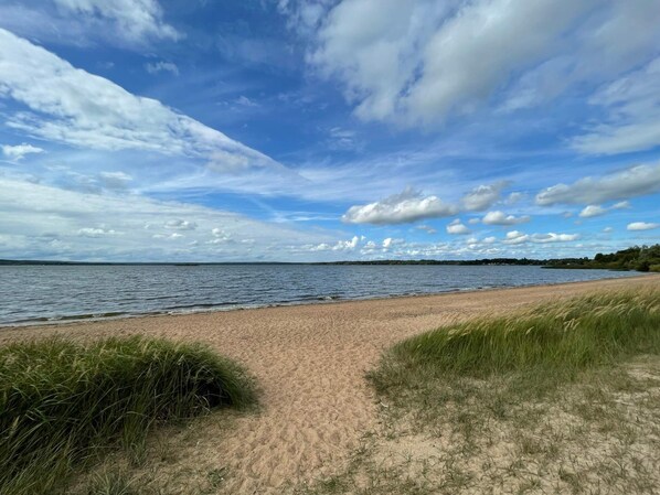 A beach with a sandy path leading to the water, surrounded by grassy areas. - 4 Person Holiday Home in Arkelstorp (Arkelstorp)