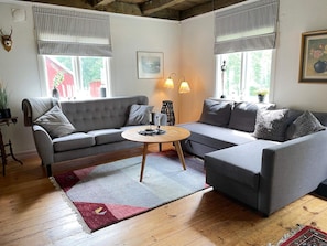 A modern living room with a grey sectional sofa, a round coffee table, and a red and grey rug. - 4 Person Holiday Home in Arkelstorp (Arkelstorp)