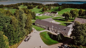 A golf course with a clubhouse, parking area, and a view of a lake. - 4 Person Holiday Home in Arkelstorp (Arkelstorp)