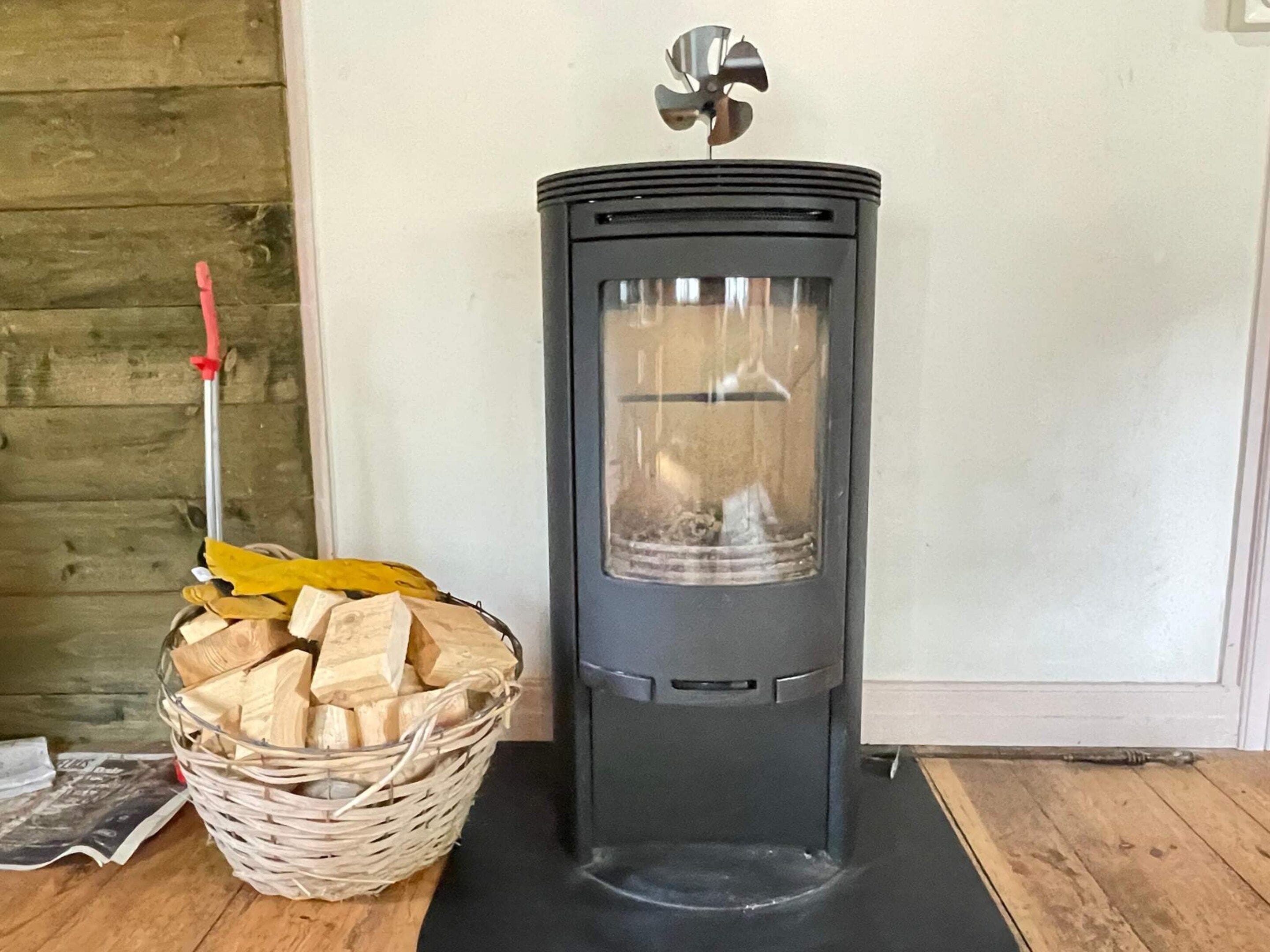 A wood-burning stove with a basket of firewood beside it.