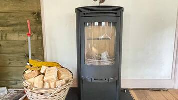 A wood-burning stove with a basket of firewood beside it.