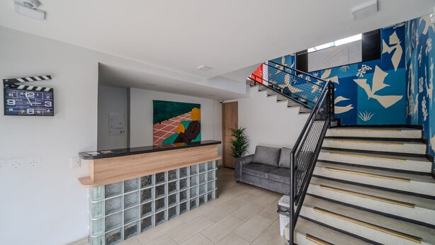 A modern interior with a reception desk, a staircase with a blue and white design, and a grey sofa. - Nice Loft @Chapinero close to Movistar Arena (Bogotá)