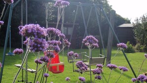 Een tuin met een schommel, een houten omheining en een gazon.