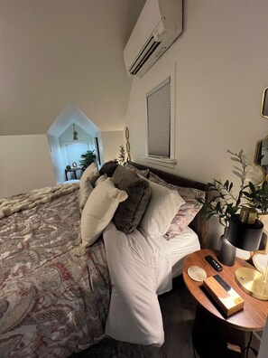 Une chambre à coucher avec un lit, une table de chevet, une lampe et une vue sur un balcon.