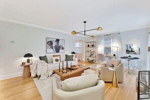 Uma sala de estar moderna com um sofá, poltronas, uma mesa de centro e um espaço de jantar com mesa e cadeiras.